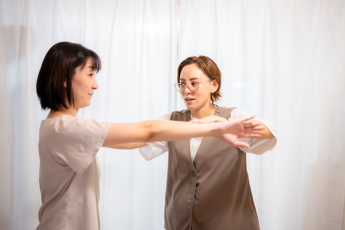 向かい合って腕を伸ばし、キネシオロジーのワークを行うセッションの様子